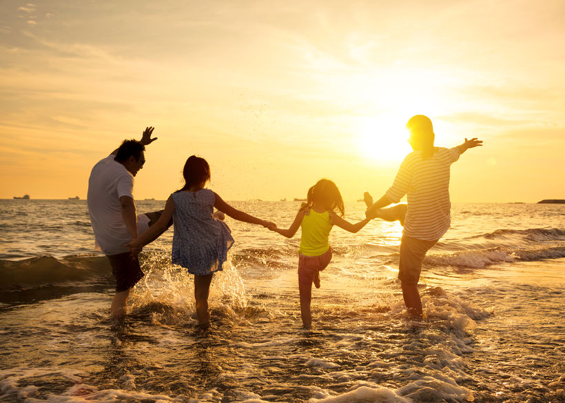 A family is playing in the water at the beach - Manning Insurance Services.