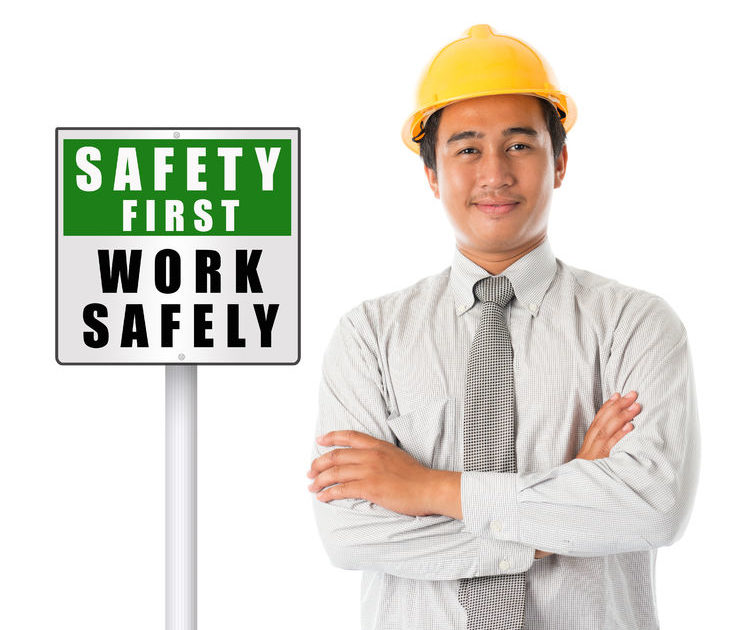 A man in a shirt, tie and Hard Hat next to a Safety First - Work Safety Sign - Manning Insurance Services.
